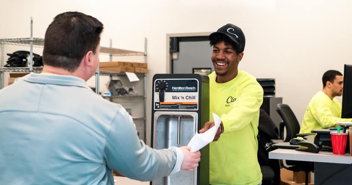 A clark service technician handing a client paperwork